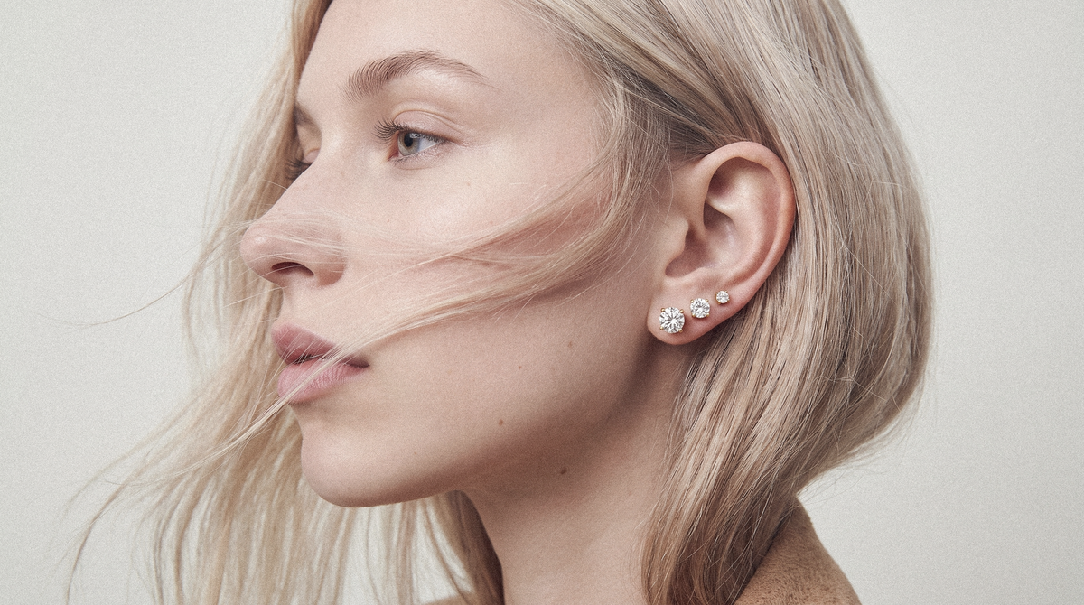 Woman wearing three diamond stud earrings